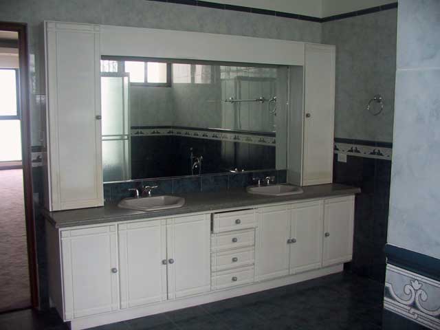 Photo example of a bathroom with blue and white tiles and white bathroom furniture and glass shower sliding doors.