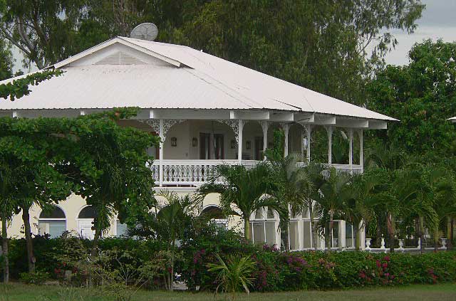 Photo example of a beach house built in a French Colonial Style with extensive terraces around the house and painted all in white