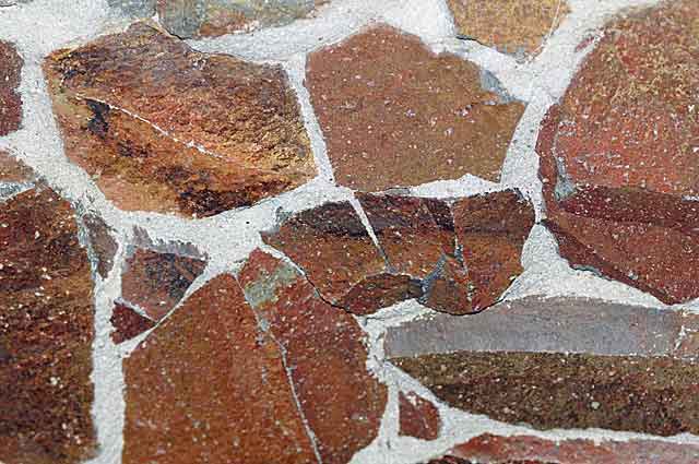 Example photo of a decorative stone wall in brick red tones with natural cement plaster